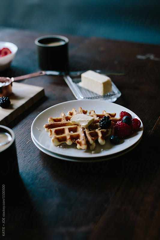 Waffles on a plate topped with berries and butter