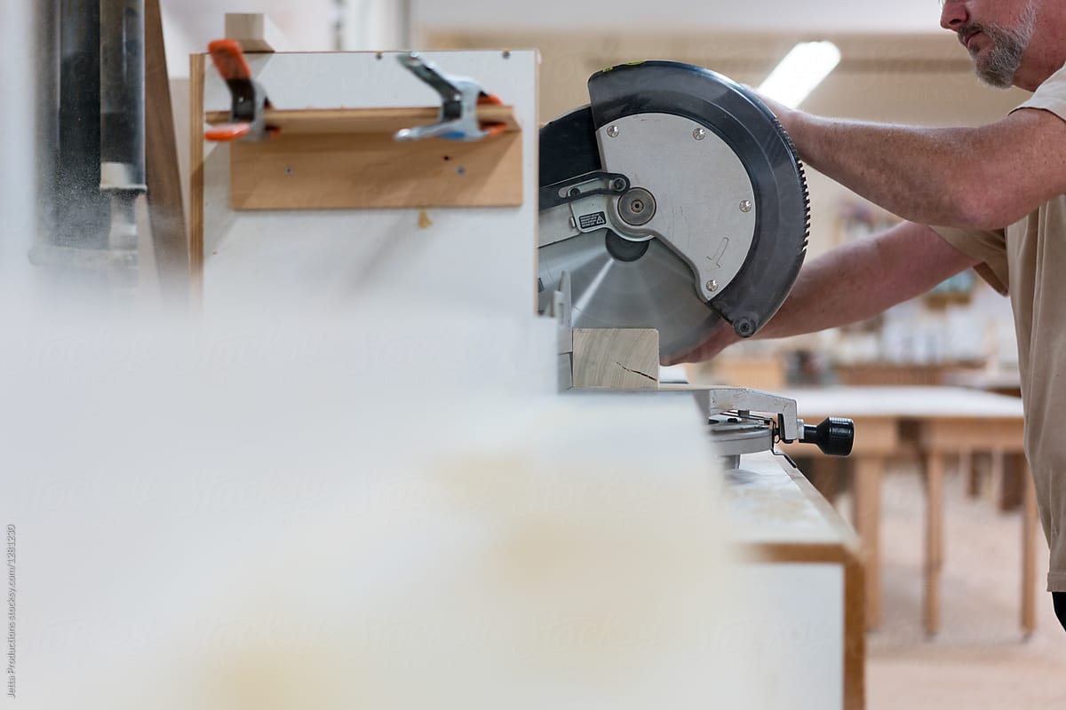 Partial view of carpenter using a miter saw in a cabinet shop