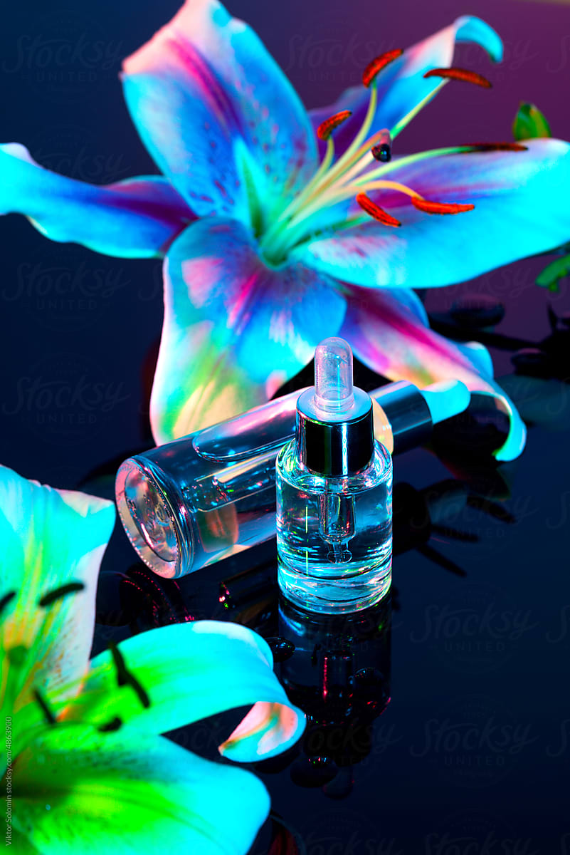Bottle of essential oil and serum with neon flowers
