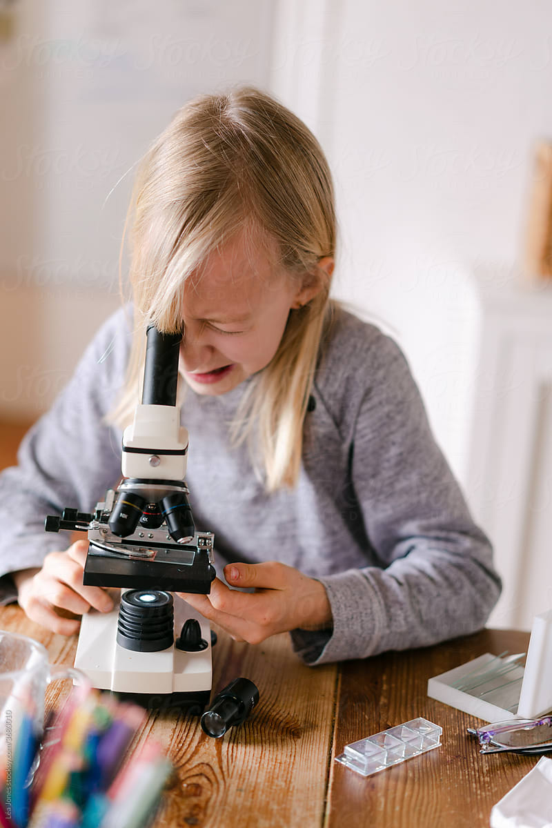 young girl looking through microscope