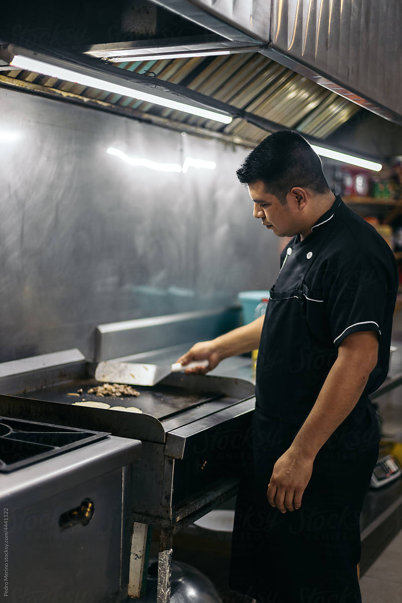 Mexican chef cooking tacos in professional kitchen