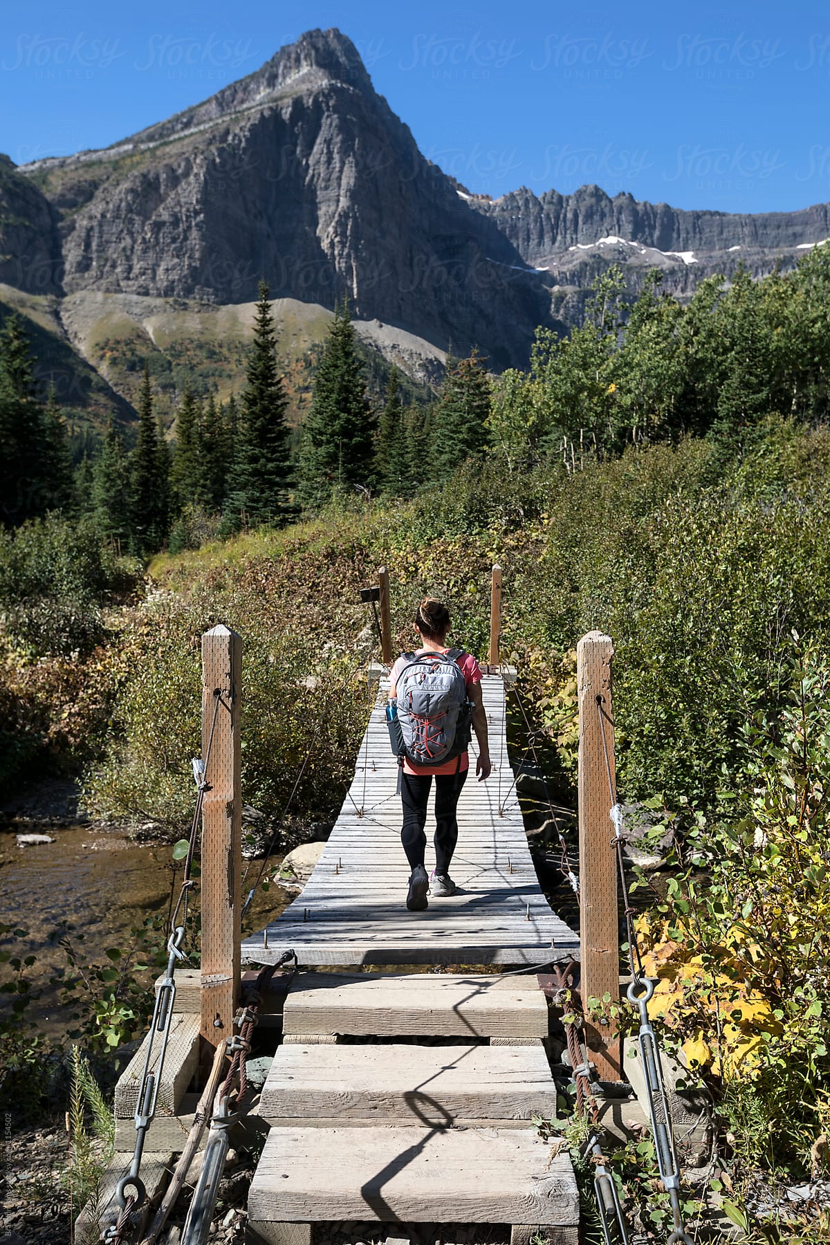 Woman Hikes Across a Bridge in Glacier National Park