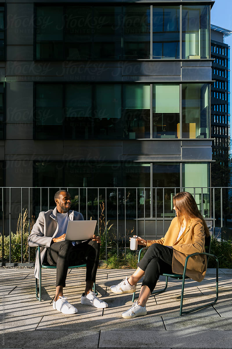 Two colleagues talking on the terrace of a modern corporate building