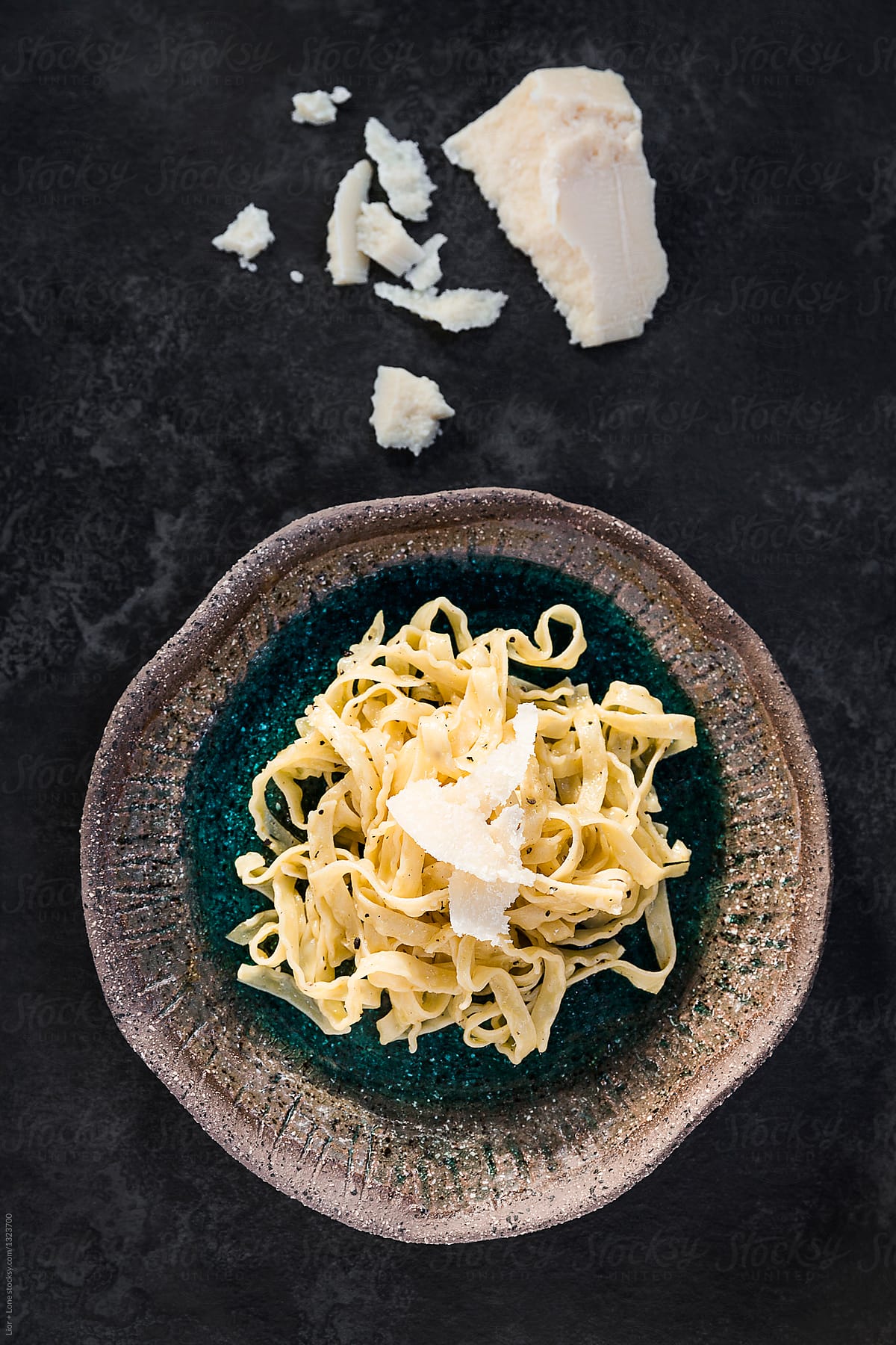 fettuccine cacio e pepe pasta in ceramic bowl with cheese around