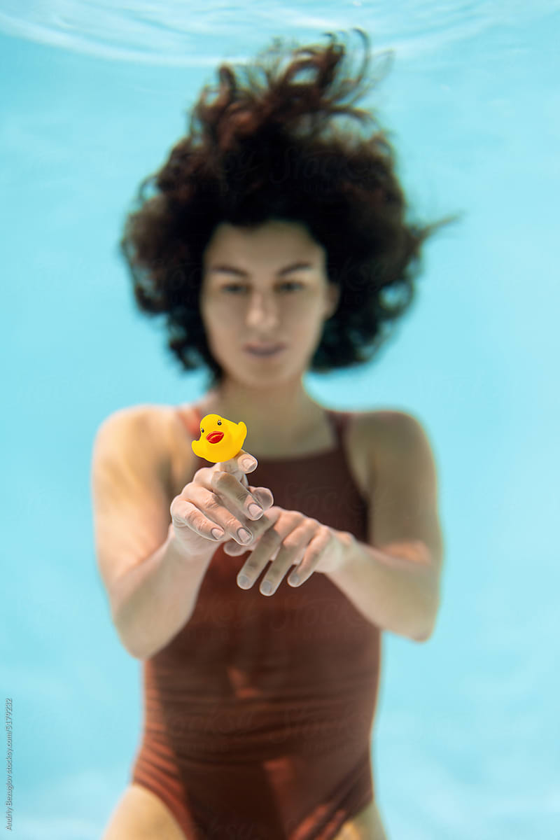 Brunette model posing underwater with toy duck
