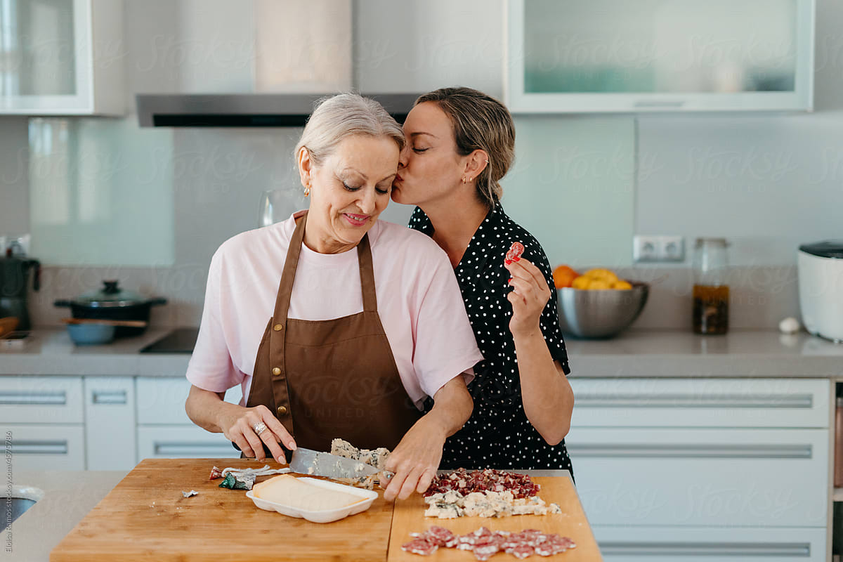 Mother and affectionate daughter preparing snacks in kitchen