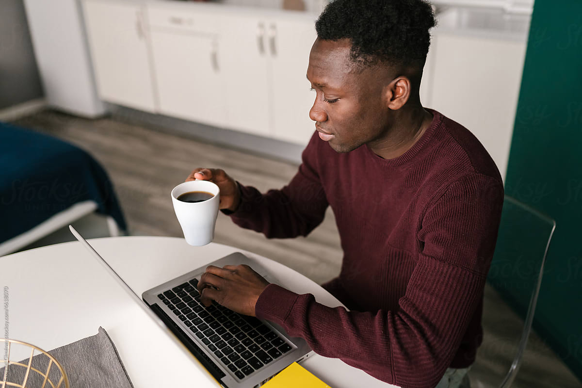 African American man with coffee using laptop