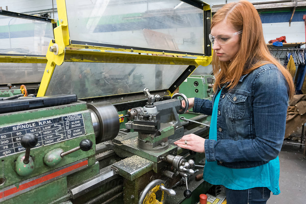Female company executive tries out lathe in machine shop