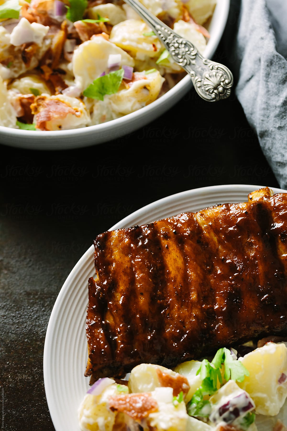 Plate of ribs with bowl of potato salad