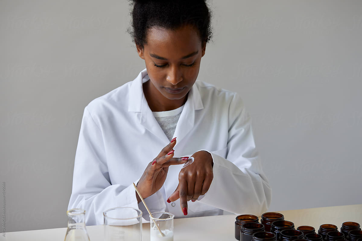 Black pharmacist applying cream on hand