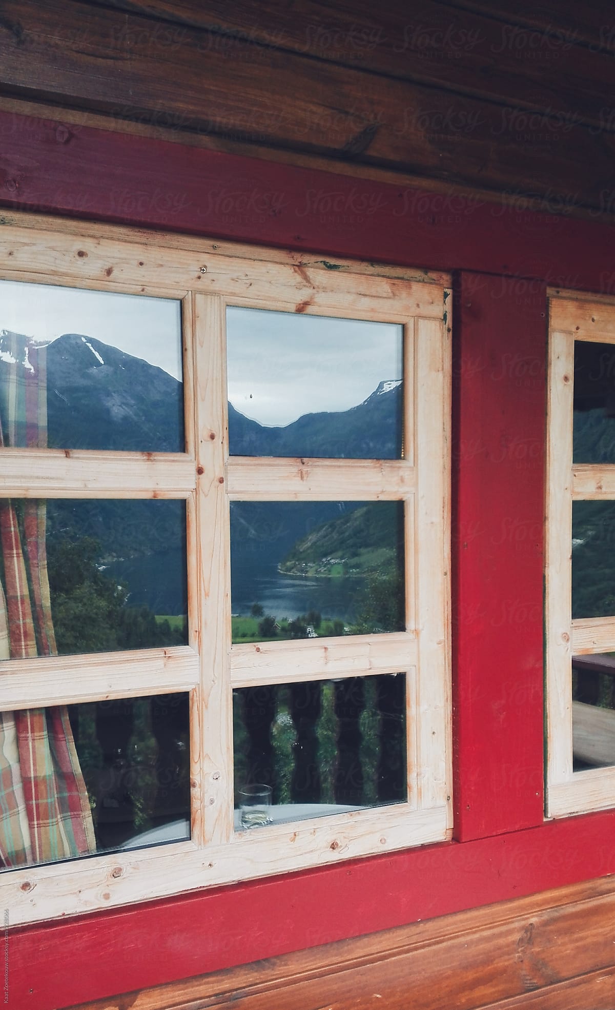 Mountain and fjord view reflected in cozy cabin window