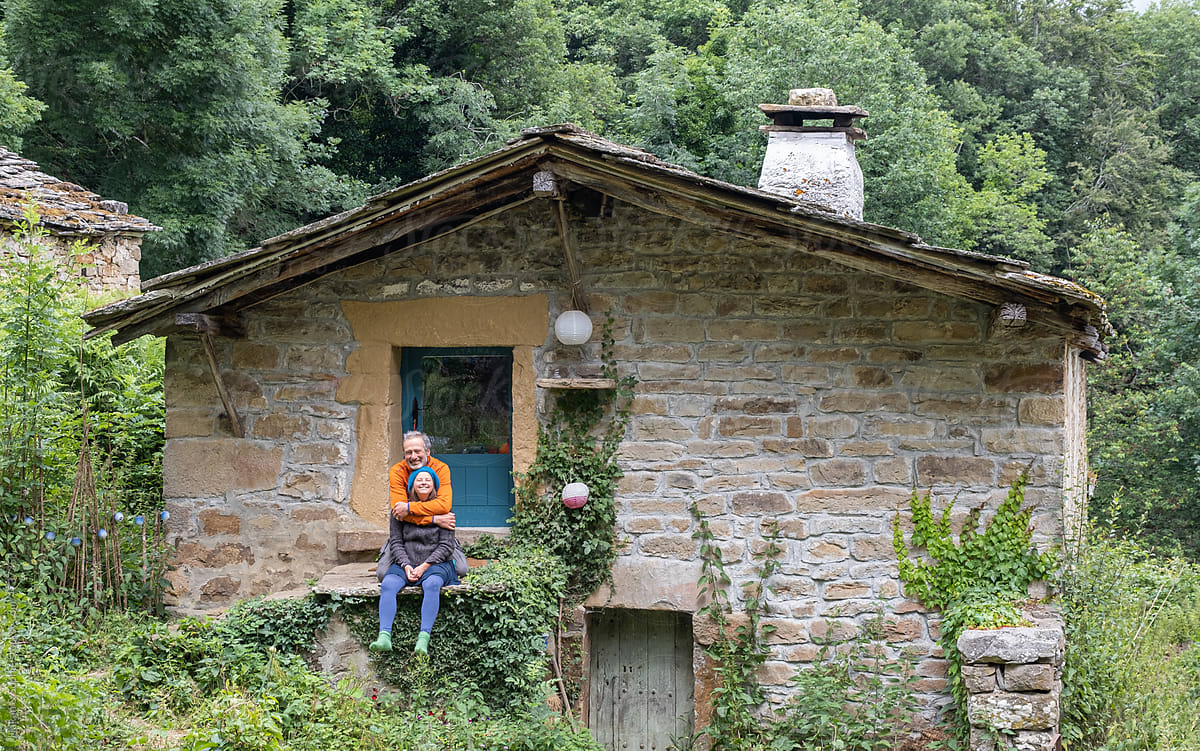 couple posing in front of their rural stone house