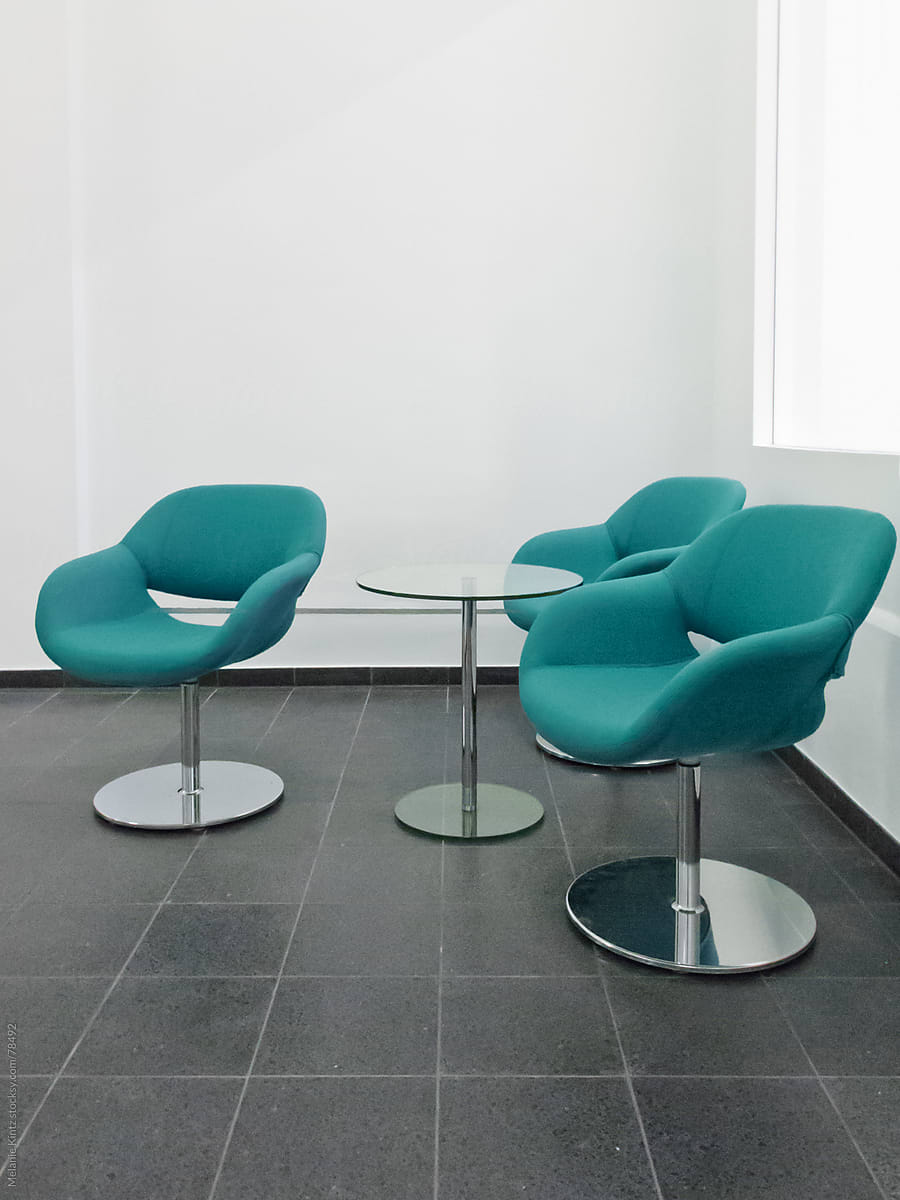 Three blue-green colored chairs in a waiting area