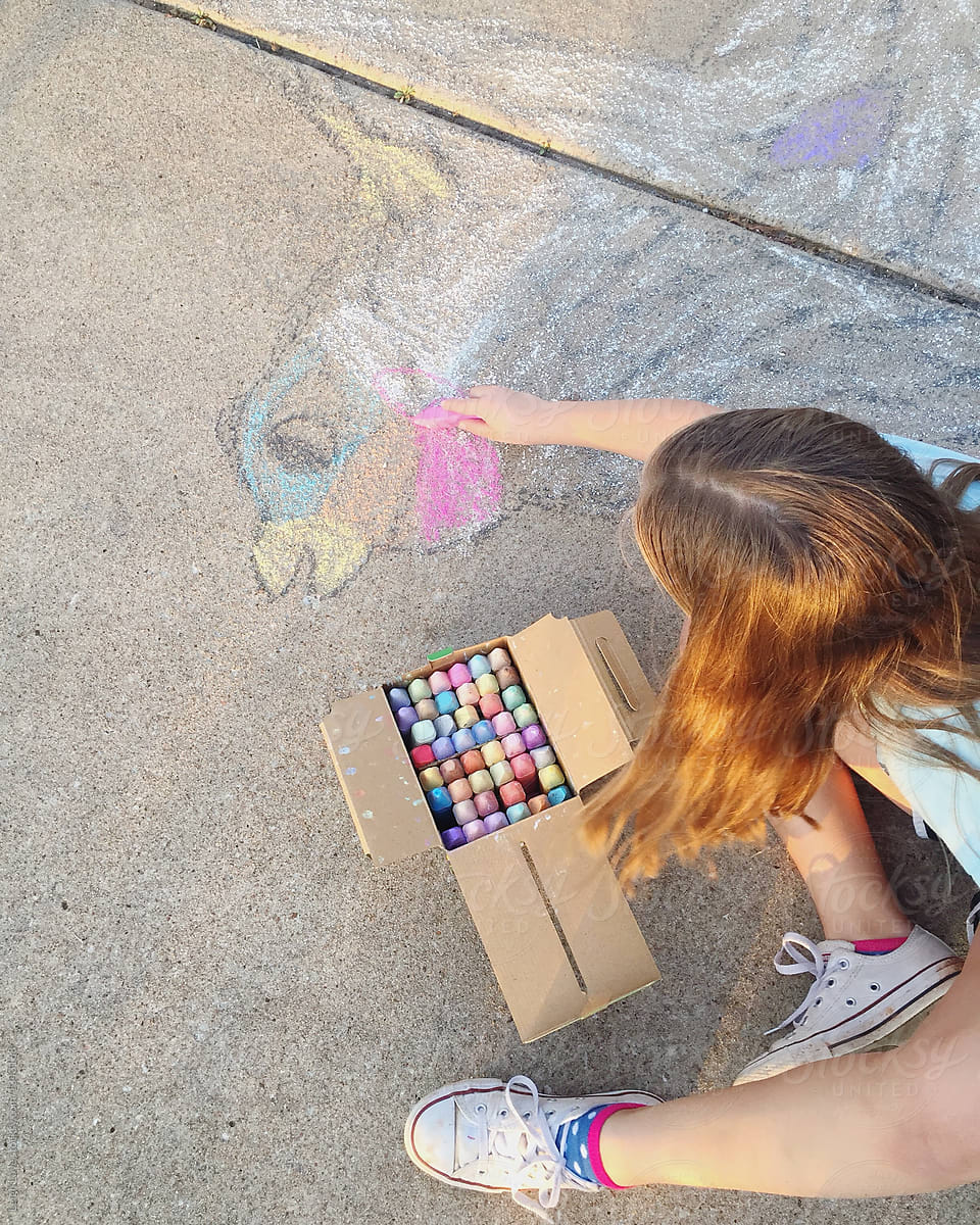 Young Girl Drawing A Bird With Sidewalk Chalk
