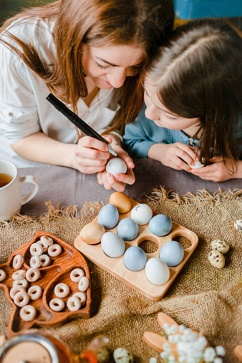 Easter with mother and little daughter painting eggs and drawing