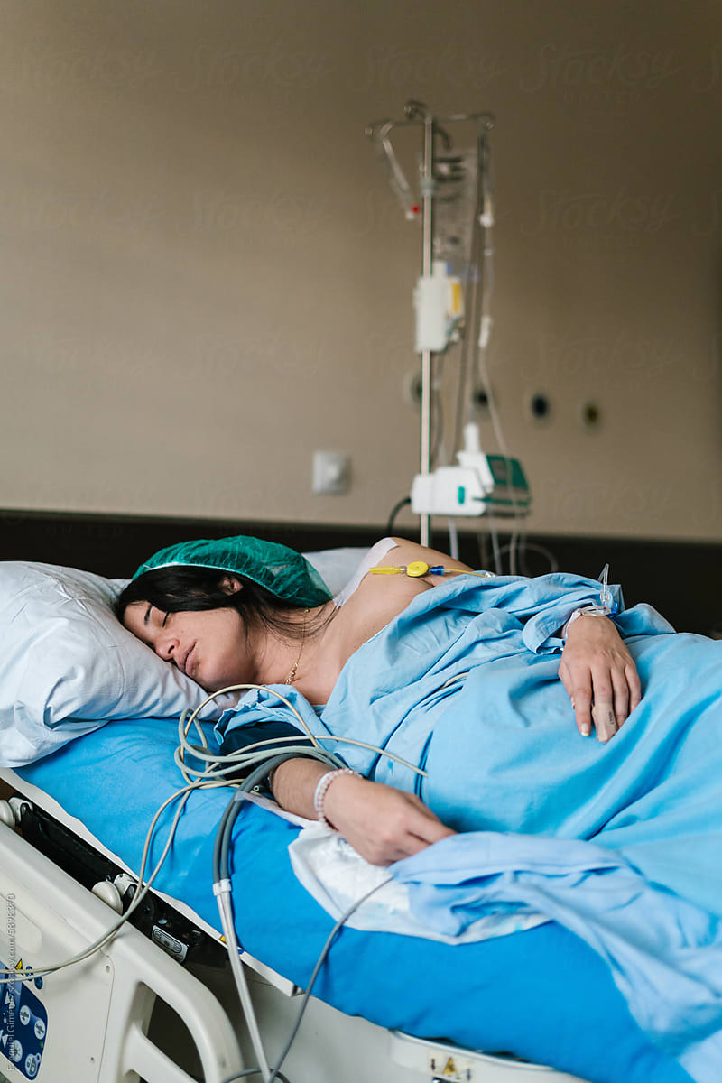 Pregnant woman sleeping in hospital bed under blanket