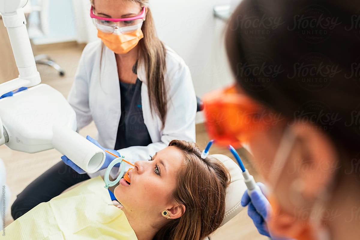 Dentist and assistant doctor during a dental intervention with a patient.