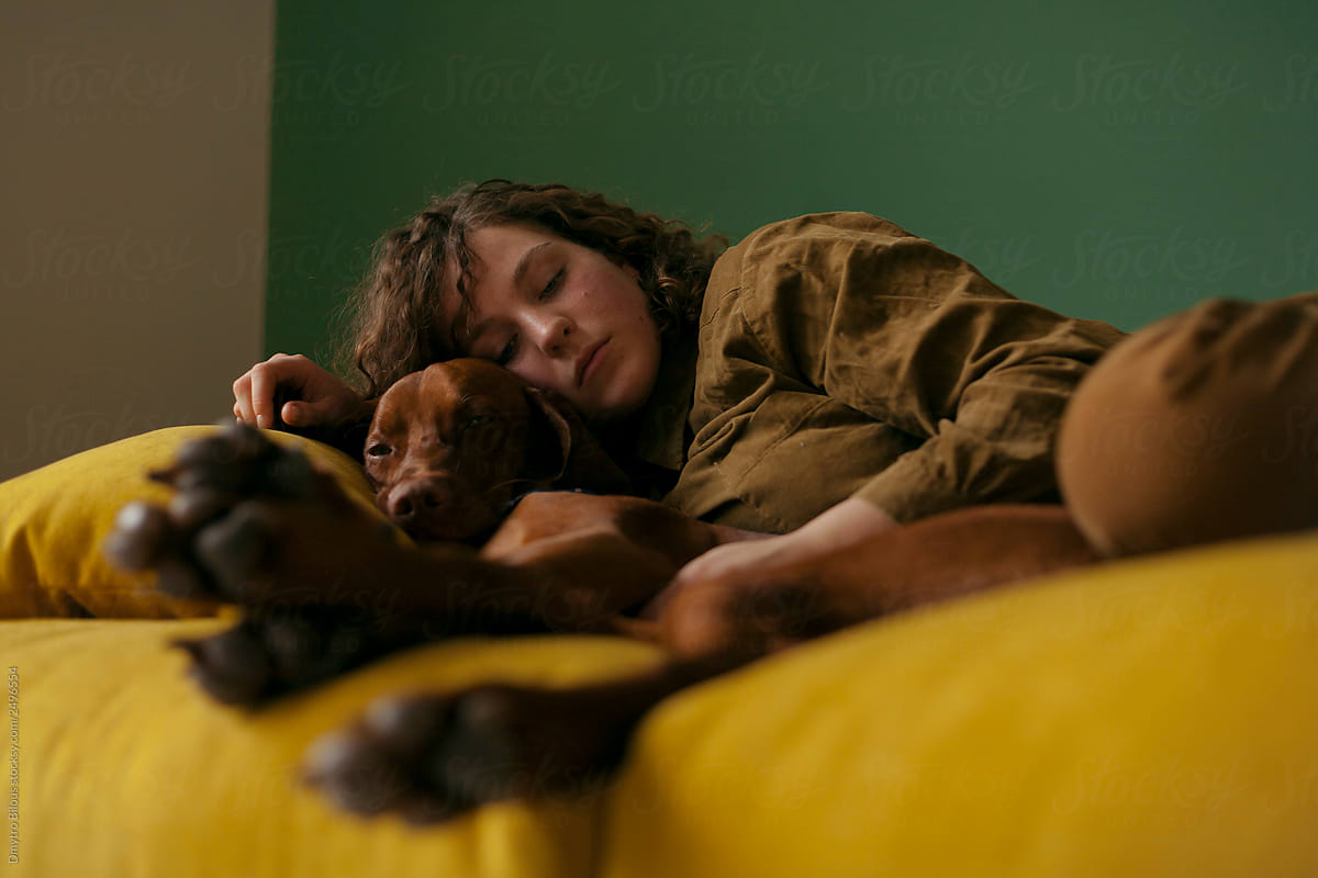 girl lying on the couch and hugging a dog angle from below