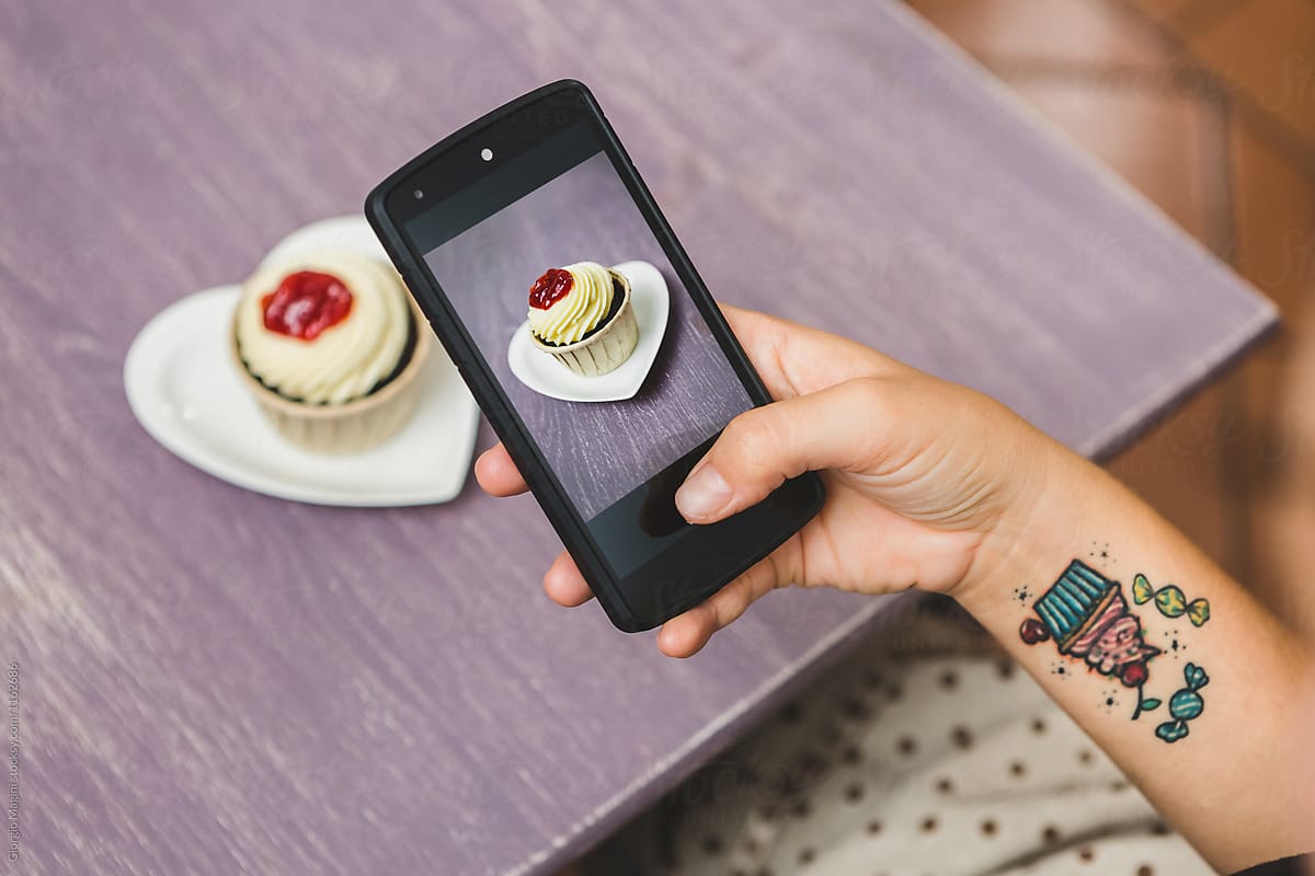 Woman Taking Pictures of a Cupcake with a Mobile Phone