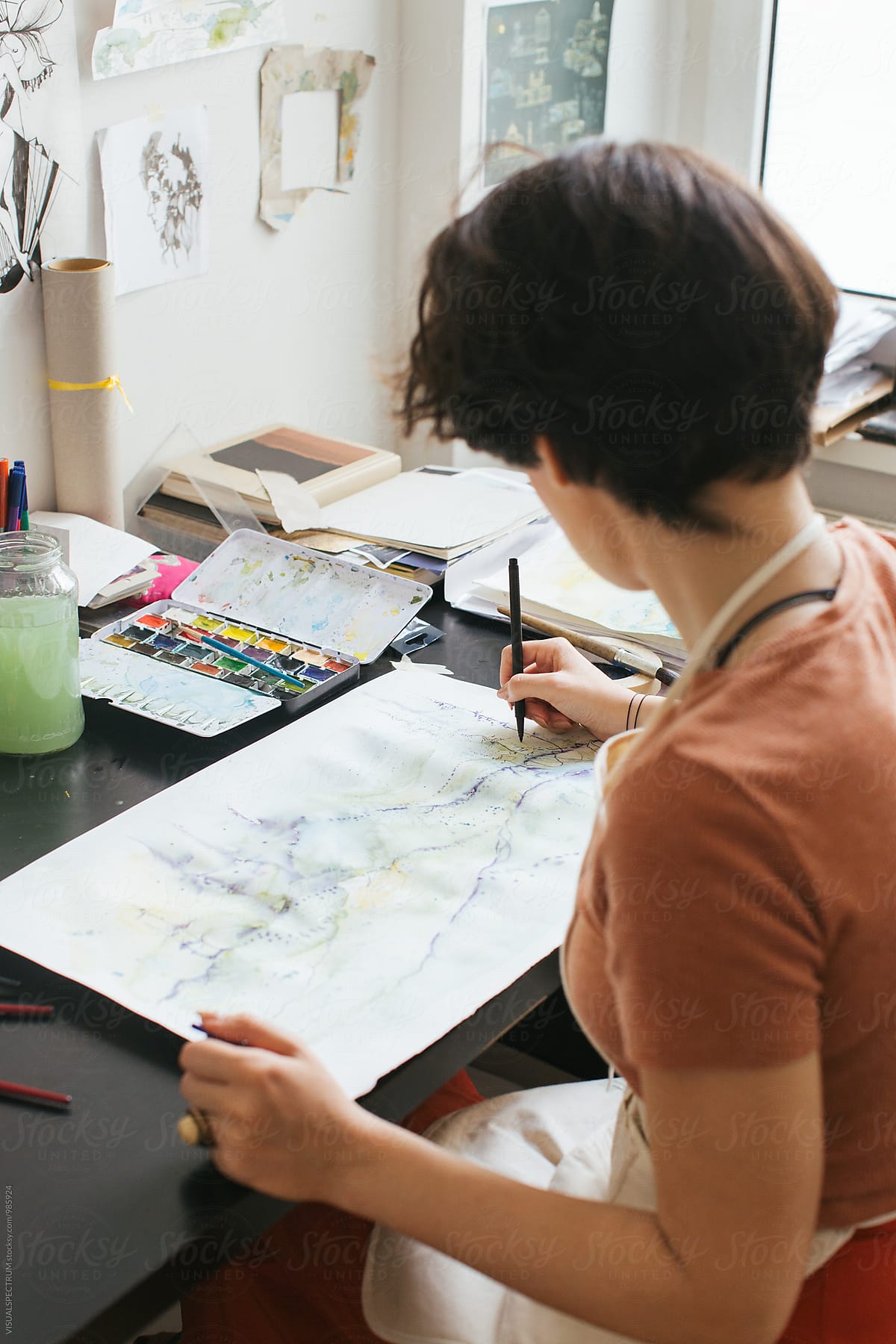 Art Studio - Young Female Brunette Painter Sitting on Desk and Using Art Pen