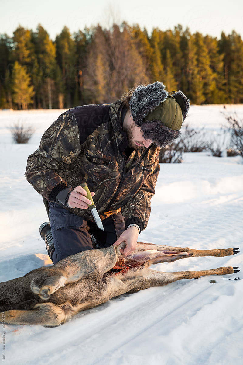 Hunter skinning deer in snow