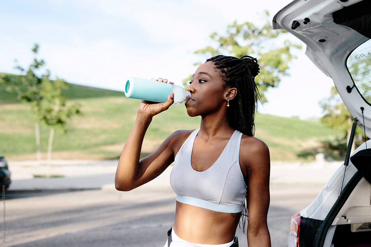 Woman drinking water from a bottle before start training