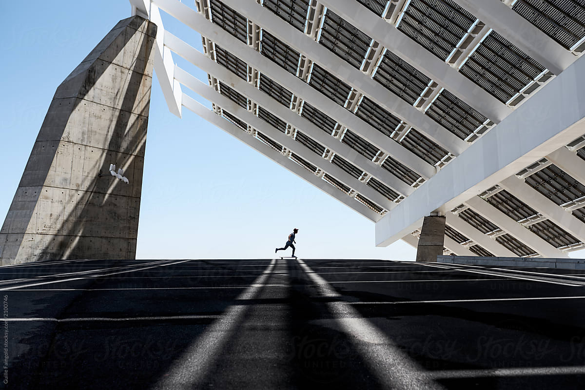 Man riding skate under a sustainable photovoltaic installation
