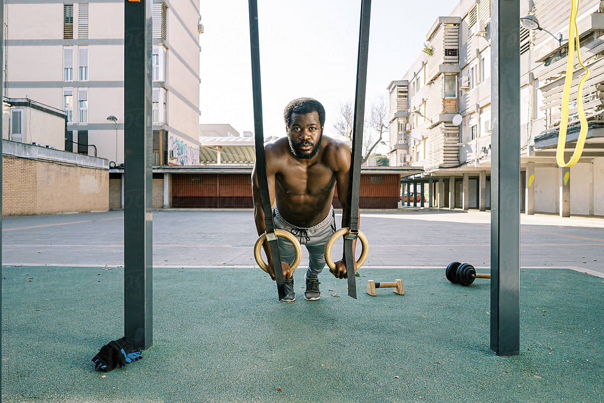 Athletic man working out with rings on sports ground