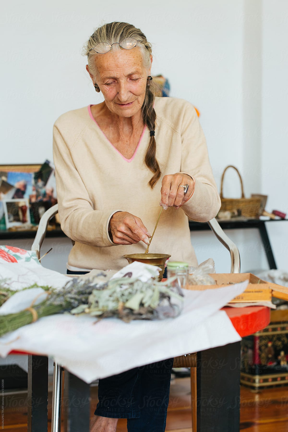Indoor Portrait of Elderly Female Herbalist Making Natural Incense Stick