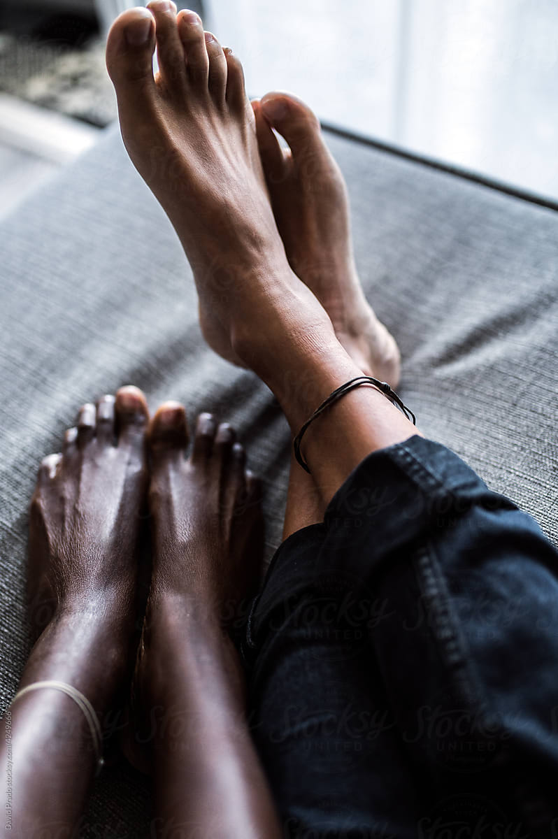 multiethnic foot of couple relaxing on sofa