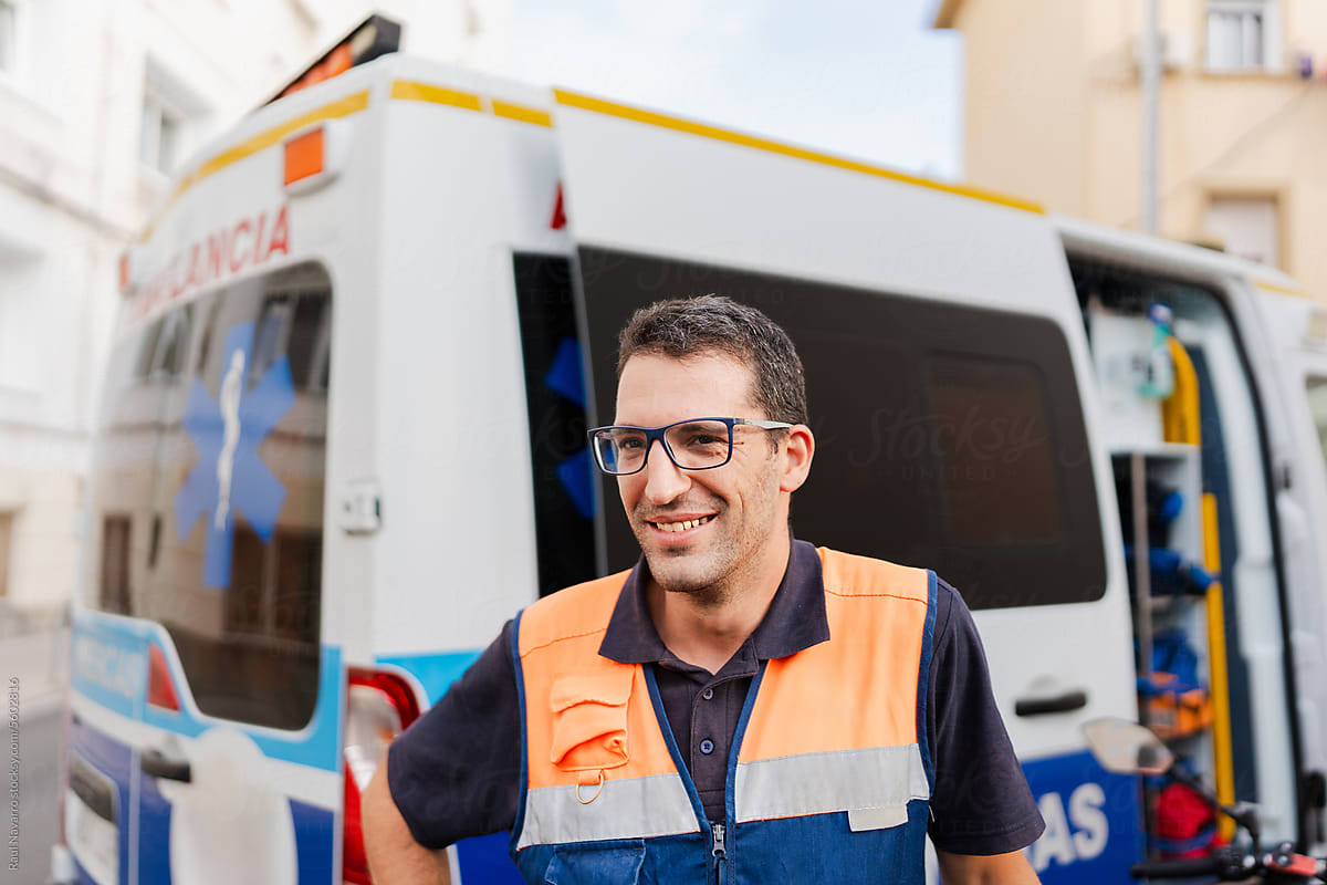portrait of a smiling paramedic next to an ambulance.