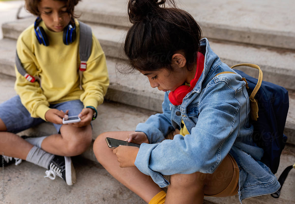 Kids sitting on the stairs using their phone