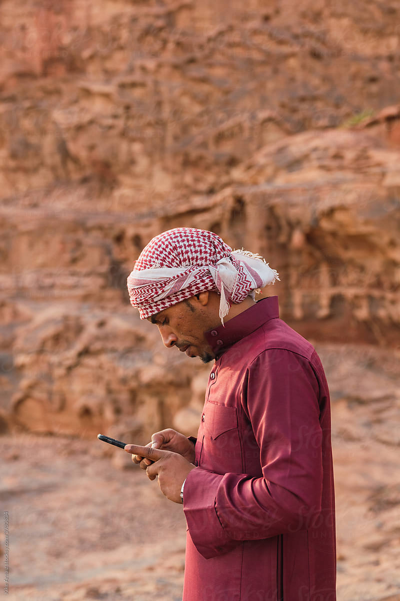 Arabic man using smartphone near mountains