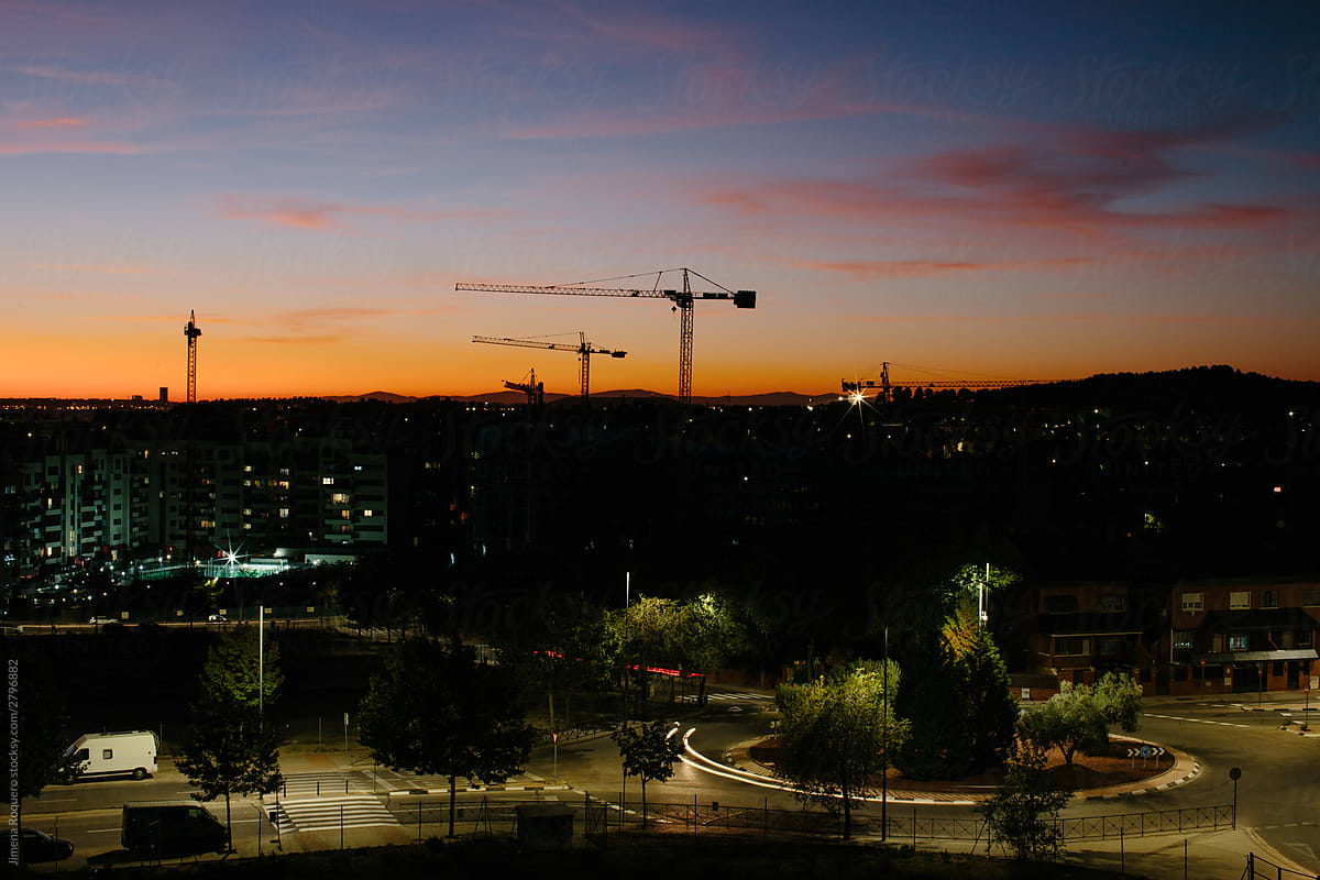 Open shot of a city at sunset with some construction cranes