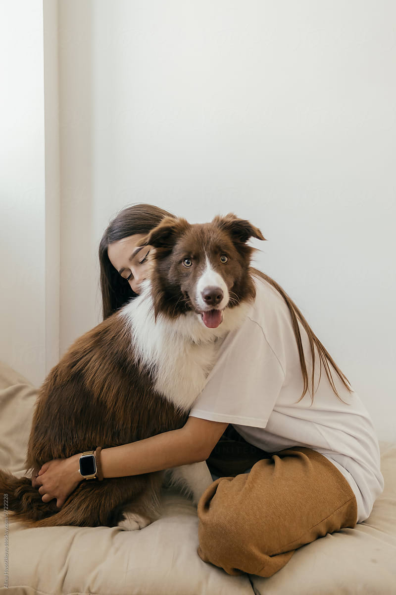 Happy young woman hugging dog at home