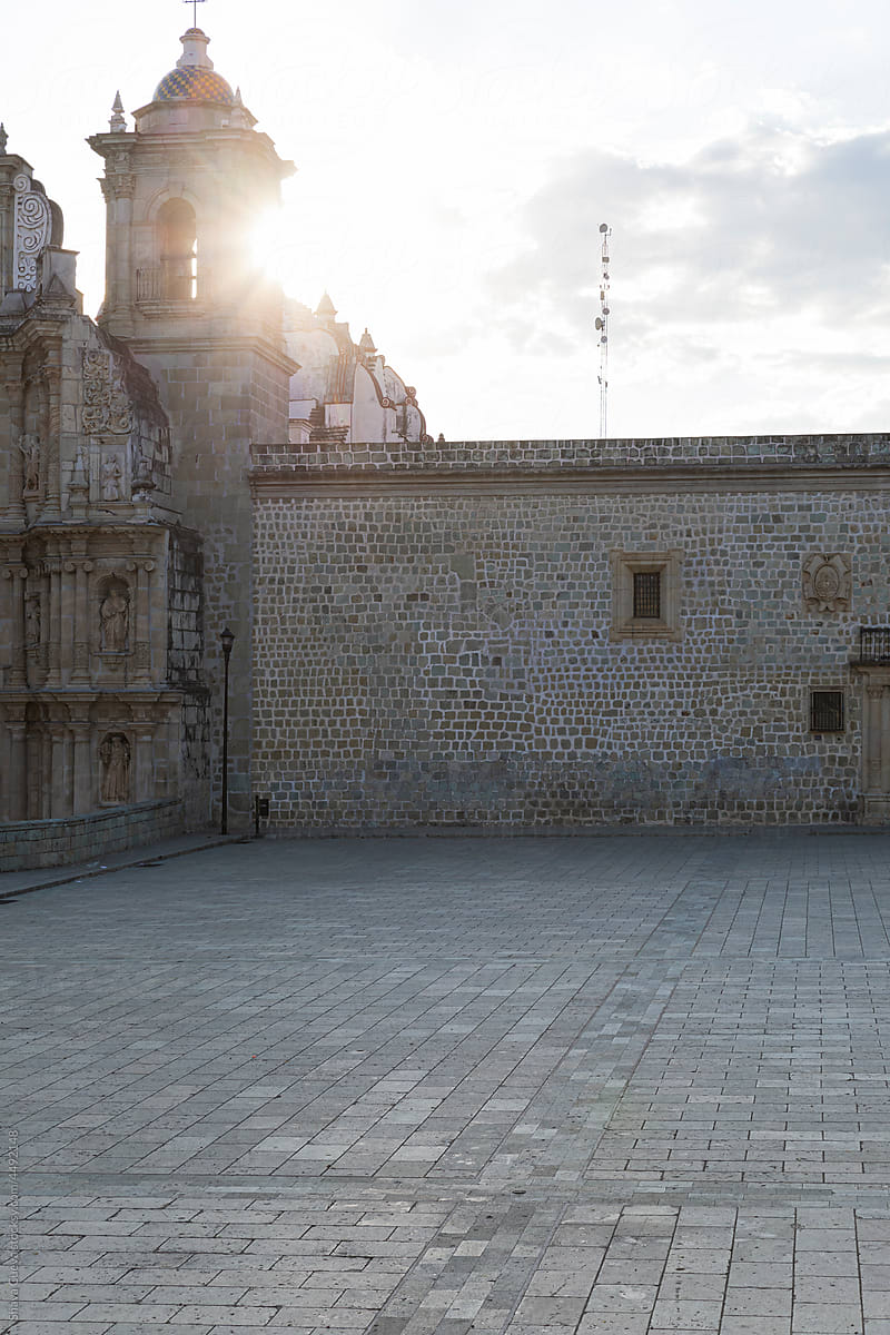 Empty patio of a stone church with the sun in the background