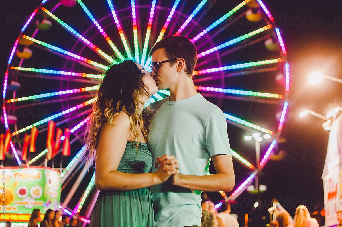 A young couple in front of a ferris wheel