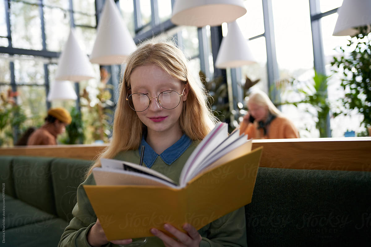 Focused woman reading novel in cafe