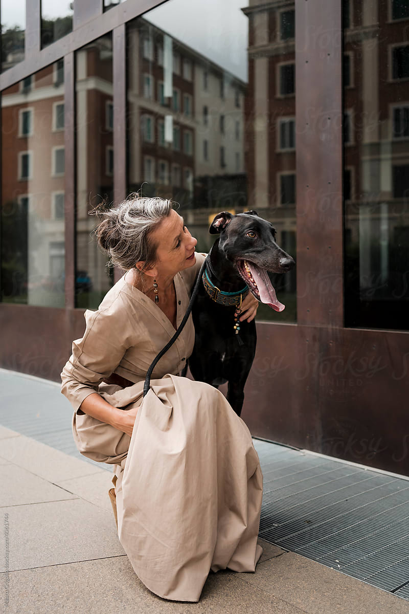 An elegant Woman embraces her dog in the city