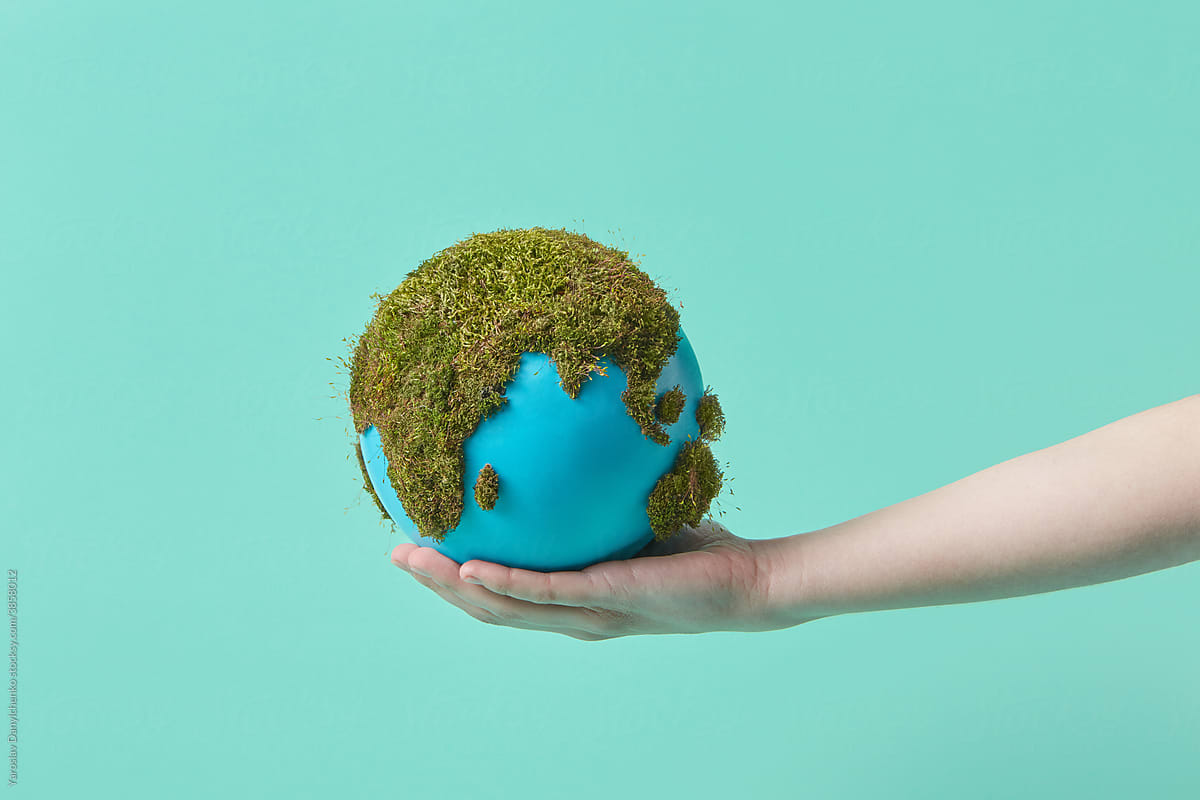 Woman holding earth globe with green moss on hand