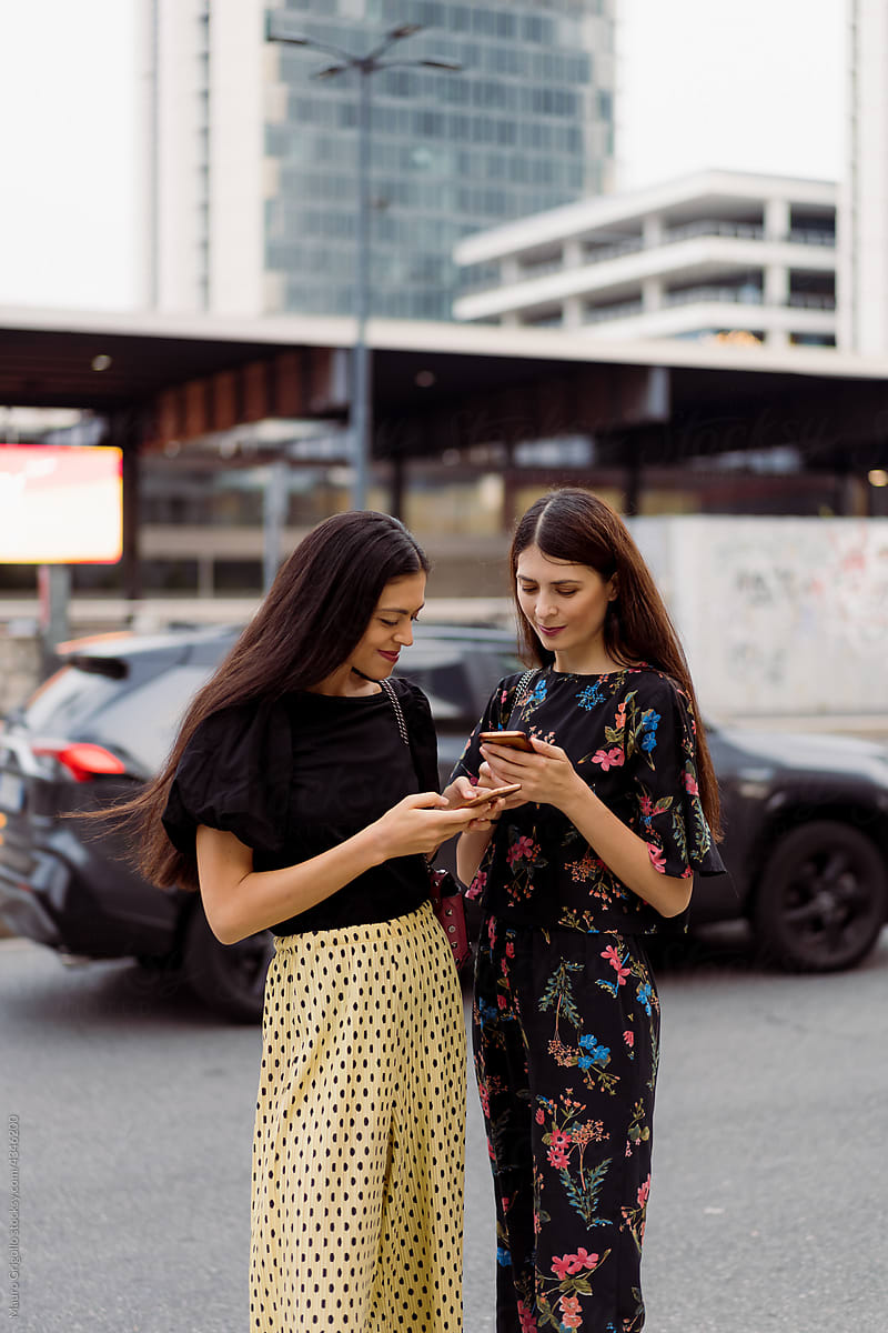 Girlfriends using a smartphone outdoor in town
