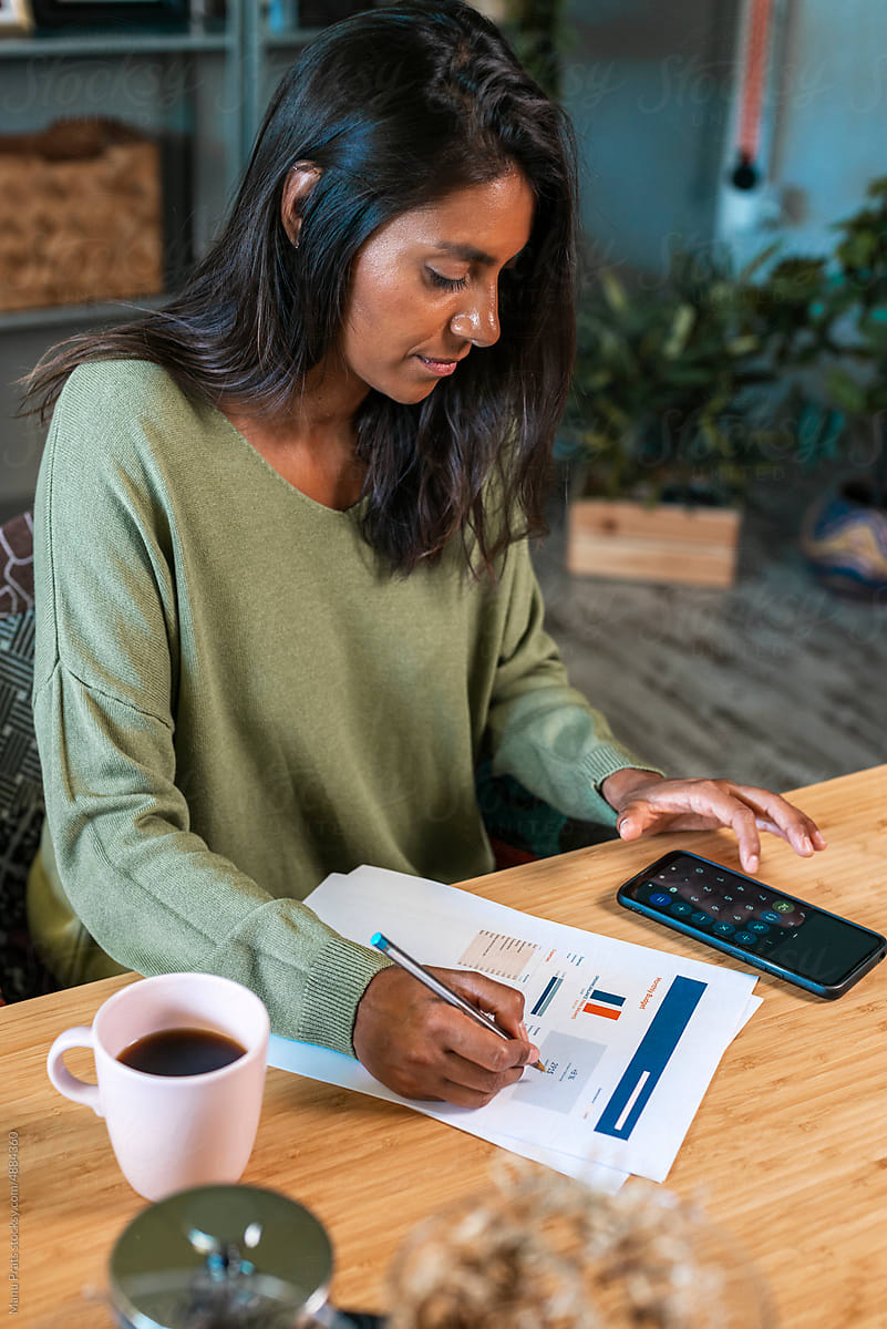 Hispanic woman calculating expenses at home