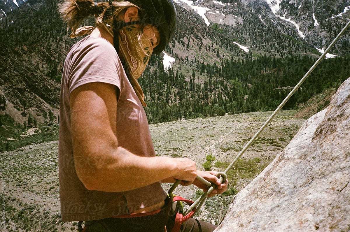 Climber tying rope to harness