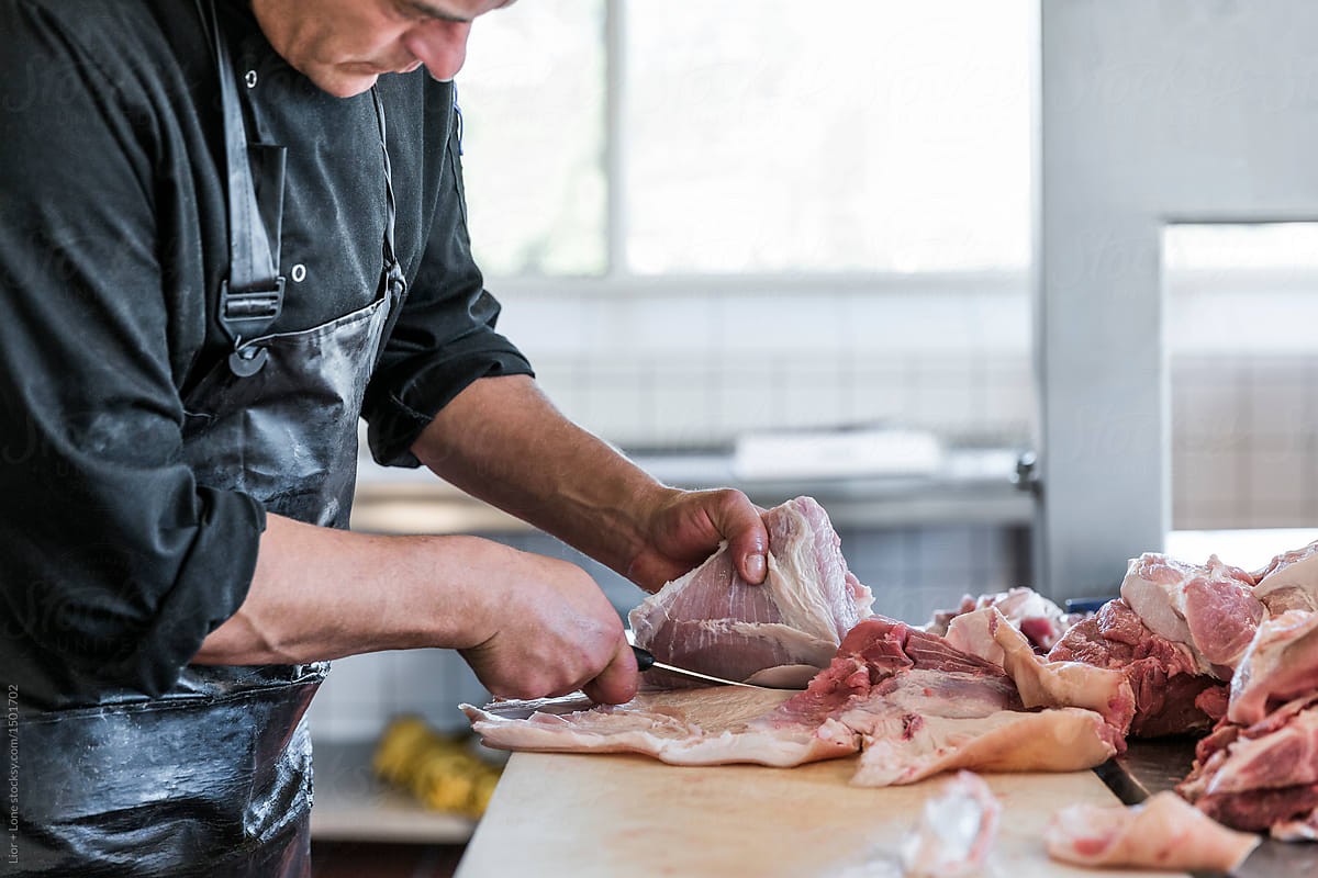 Man working as butcher cutting a piece of meat