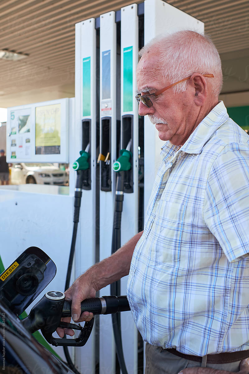Senior man at gas station filling car