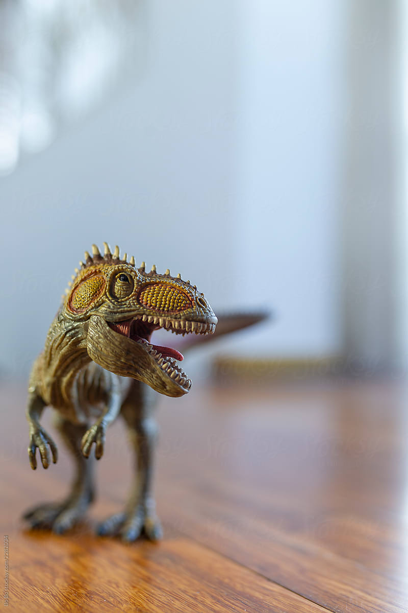 Toy dinosaur in sunset light on the floor at home
