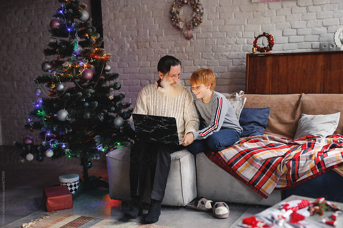 Boy and retired man using laptop and relaxing on sofa