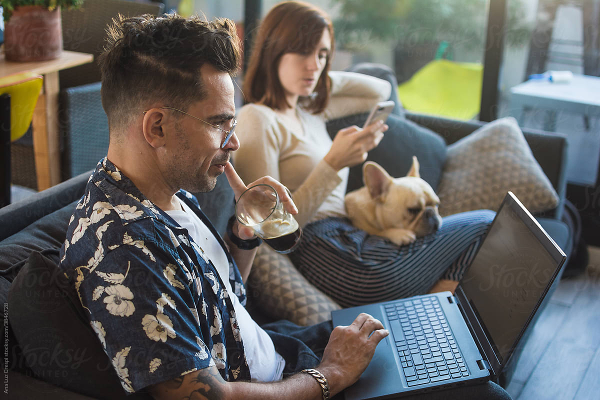 Candid moment of couple with dog using technology