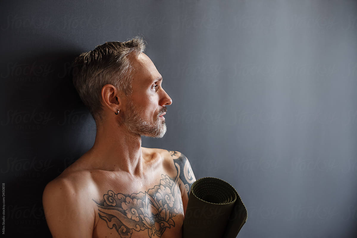 Mature man with mat in yoga studio