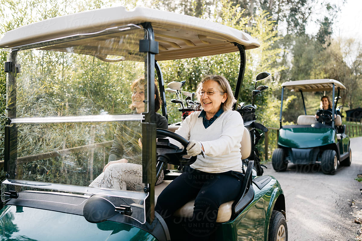 Women driving golf carts in park